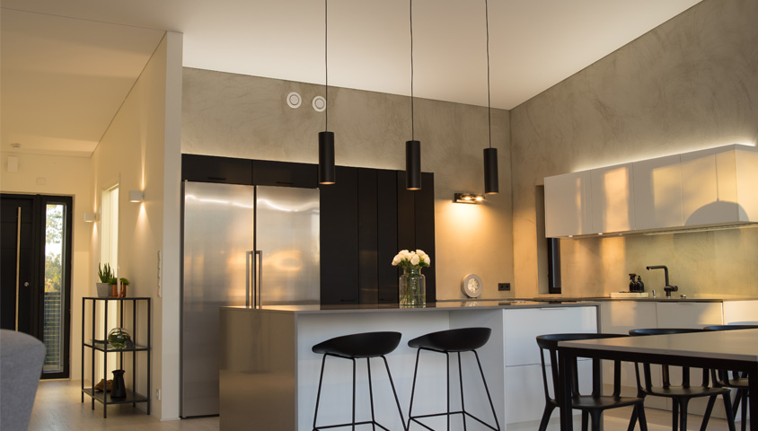 A black, silver and white luxury kitchen renovation with warm natural lighting, a kitchen island and hanging lights.