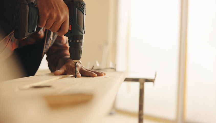 A kitchen renovation service team member drilling into wood as part of a luxury kitchen renovation.