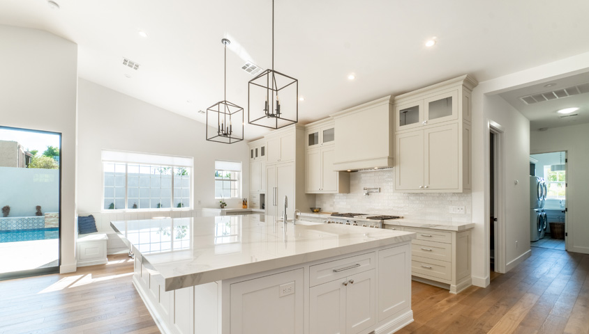 Luxurious white and cream custom kitchen cabinets with profiled doors and stone countertops.