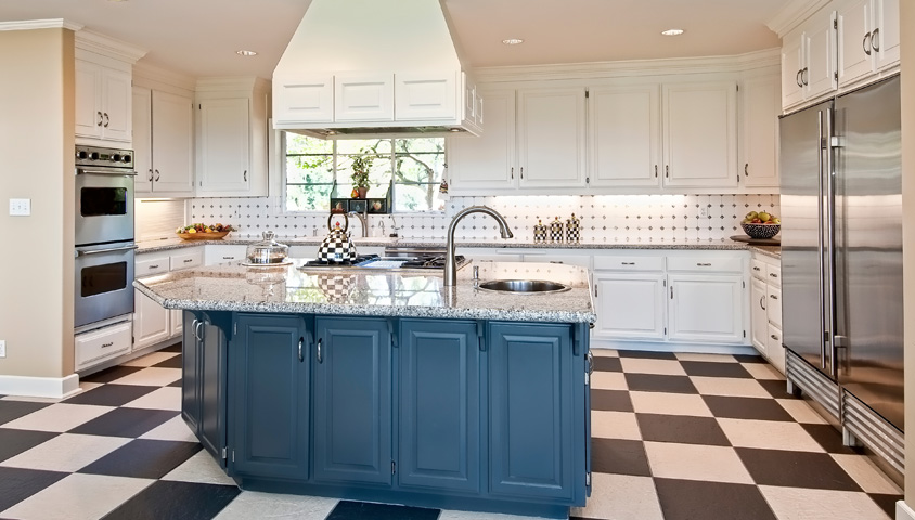 A modern angled kitchen island featuring a granite countertop and a blue finish inside a modern renovated kitchen