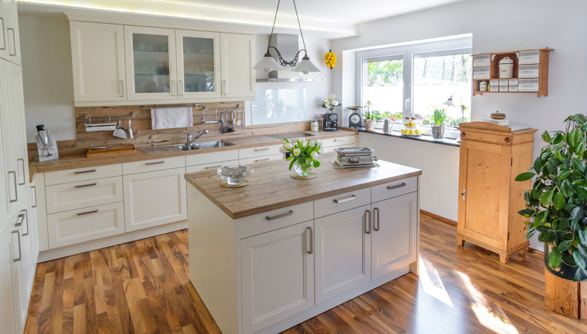 A country-style modern kitchen with central country-style kitchen island and wooden detailing with cabinetry 