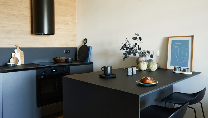 A newly renovated sleek and modern black kitchen with a small kitchen island featuring room for two small stools