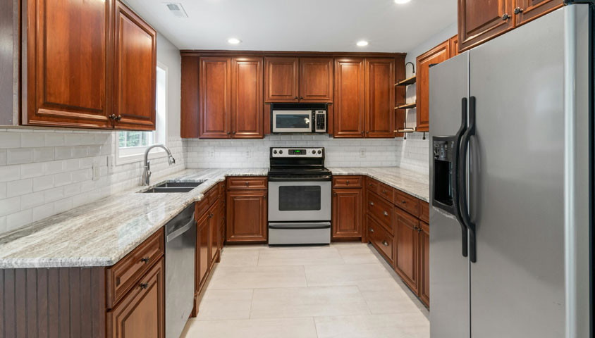 A newly renovated luxury wooden kitchen with stripey grey granite and simple white wall and floor tiles