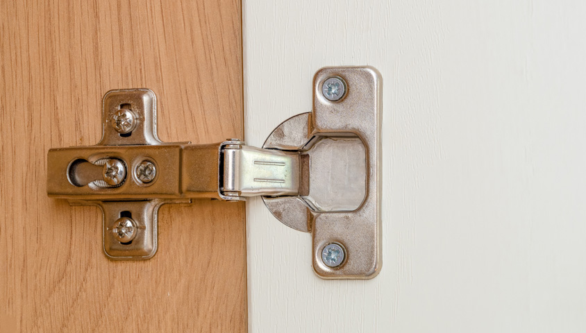 The steel hinge on a new white and wood kitchen cabinet made for a kitchen cabinet renovation.